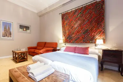 a bedroom with a large bed and an orange couch at AinB B&B Born-Via Laietana in Barcelona