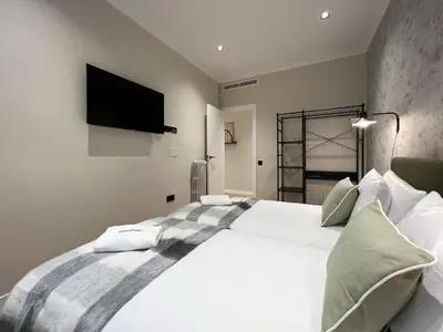 a bedroom with a large white bed with a flat screen tv at Stay U-nique Apartment Muntaner in Barcelona