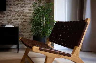 a wooden chair in a living room with a plant at Stay U-nique Apartment Muntaner in Barcelona
