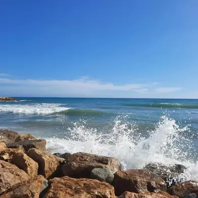 a wave crashing on the rocks in the ocean at Apartamento Sunny Home in Cunit