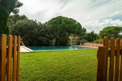 a fence in a yard with a swimming pool at Casa rural El Bruguer Vell in Santa Eulalia de Ronsaná