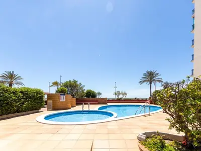 a swimming pool in the middle of a courtyard with palm trees at Apartment Garbi by Interhome in Cunit