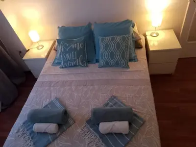 a large bed with blue pillows on it with two tables at Migjorn Apartment a place in the heart of Sitges in Sitges