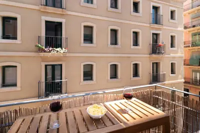 a table with a pizza and wine glasses on a balcony at Charming Seaside Apartment in Barceloneta, Renovated with Stunning Sea Views in Barcelona