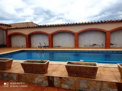 a pool with three plants in baskets next to a building at Ca La Montserrat - Wine Rural House in San Martín Sarroca
