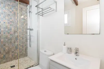 a white bathroom with a shower and a sink at Apartamentos Mayor by Habama Group in Sitges