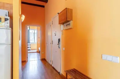 a hallway with orange walls and a kitchen with a refrigerator at 4179 - AB Verdi Villa de Gracia Apartment in Barcelona