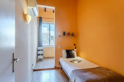 a small room with a bed with an orange wall at 4179 - AB Verdi Villa de Gracia Apartment in Barcelona