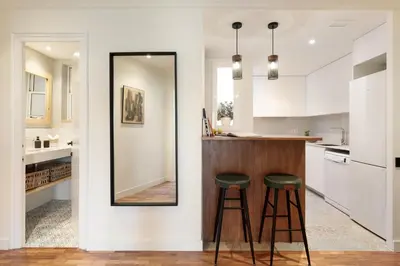 a kitchen with a counter with two stools and a mirror at Enjoy Apartments La Riera Principal in Barcelona