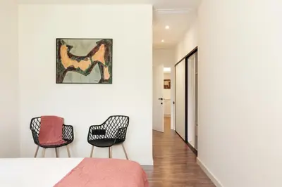 a bedroom with two chairs and a painting on the wall at Enjoy Apartments La Riera Principal in Barcelona