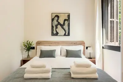 a white bedroom with a large bed with two pillows at Enjoy Apartments La Riera Principal in Barcelona