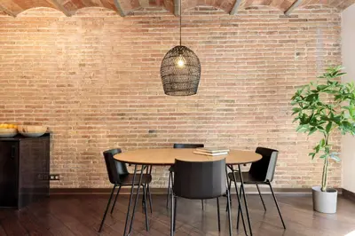 a dining room with a table and a brick wall at Enjoy Apartments Urban Retreat Valencia 1 in Barcelona