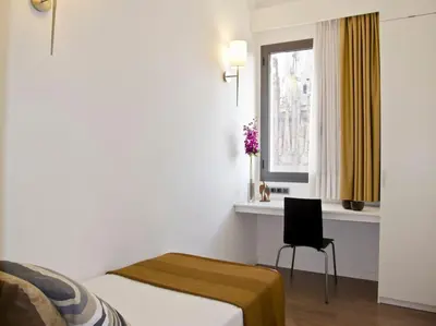 a bedroom with a bed and a chair and a window at Flat with views to Sagrada Famila in Barcelona