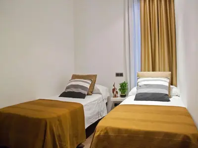 two beds in a small room with yellow sheets at Flat with views to Sagrada Famila in Barcelona