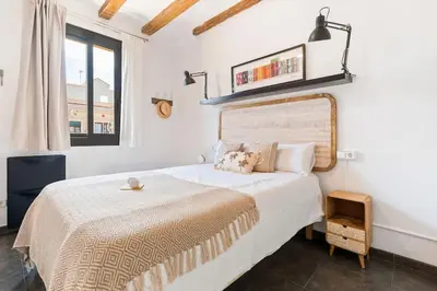 a white bedroom with a large bed and a window at Lodging Apartments Almirall Beach 52 in Barcelona