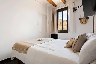 a white bed in a white room with a window at Lodging Apartments Almirall Beach 52 in Barcelona