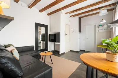 a living room with a black leather couch and a table at Lodging Apartments Almirall Beach 52 in Barcelona