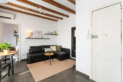 a living room with a black couch and a table at Lodging Apartments Almirall Beach 52 in Barcelona