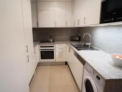 a kitchen with white cabinets and a sink and a dishwasher at Gaudi Comfort in Barcelona
