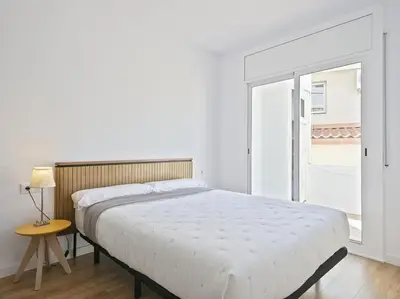 a white bedroom with a large bed and a table at Apartamento exclusivo a 15 min de Barcelona in Sant Cugat del Vallès