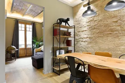 a dining room with a table and a stone wall at Sagrada266 by chicStays in Barcelona