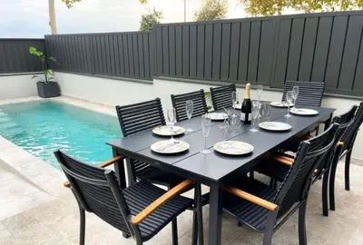 a black table with chairs and wine glasses on a patio at Elegancia y confort en Casa Moncerrat in Vilanova i la Geltrú