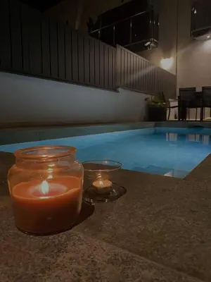 two candles on a table next to a swimming pool at Elegancia y confort en Casa Moncerrat in Vilanova i la Geltrú