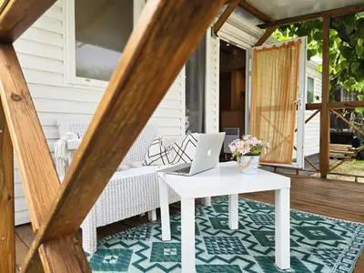 a porch with a table with a laptop on it at Camping Costa Dorada Bungalow Maia in Canet de Mar