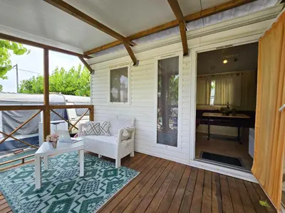 a porch with a couch and a table on a deck at Camping Costa Dorada Bungalow Maia in Canet de Mar