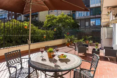 a table and chairs with wine glasses and an umbrella at Charming Central Apartment Big Sunny Terrace! in Barcelona