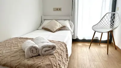 a bedroom with a bed with towels and a chair at Dúplex 2 hab con terraza by Prestigi in Terrassa