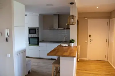 a kitchen with white cabinets and a wooden counter top at Apartment of 100m2 with sea views in Sant Vicenç de Montalt