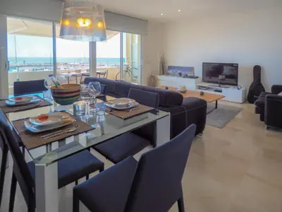 a living room with a table with chairs and a television at La Perla by Hello Homes Sitges in Sitges