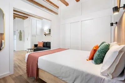 a bedroom with a large white bed with pillows at Lodging Apartments Almirall Beach 31 in Barcelona