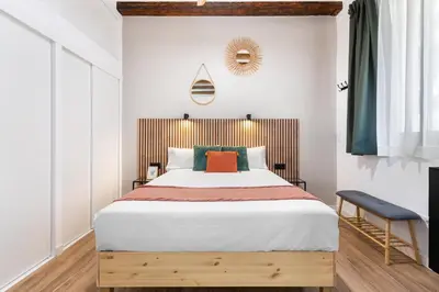 a bedroom with a large bed with a wooden headboard at Lodging Apartments Almirall Beach 31 in Barcelona