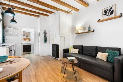 a living room with a black couch and a table at Lodging Apartments Almirall Beach 21 in Barcelona