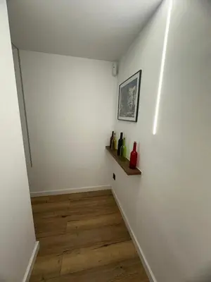 a hallway with a white wall and a shelf with bottles on it at Vidanova 2 in Vilanova i la Geltrú