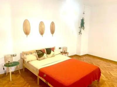 a bedroom with a bed with an orange blanket at Tucan tropical in Sabadell