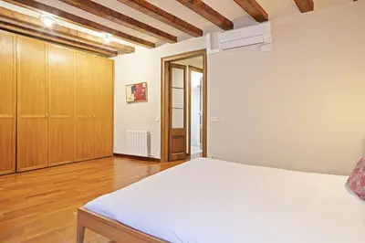 a bedroom with a white bed and wooden cabinets at Alcam Sombrerers in Barcelona