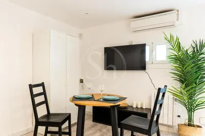 a dining room with a table and chairs and a tv at Estudio en Eixample in Barcelona
