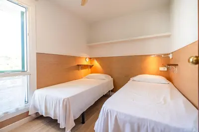 two beds in a room with white sheets at Sitges frente al mar in Sitges