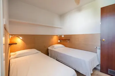 two beds in a small room with white sheets at Sitges frente al mar in Sitges