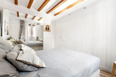 a white bedroom with a bed and a ceiling at Charming Beachside Apartment in Barceloneta in Barcelona