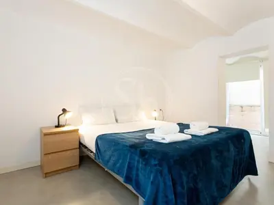 a white bedroom with a bed with two towels on it at Apartamento en Villarroel in Barcelona