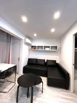 a living room with a black couch and a table at Apartamento 1 habitación cerca Sants-Estación in Barcelona