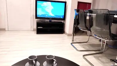 a room with chairs and a television with mugs on a table at Apartamento 1 habitación cerca Sants-Estación in Barcelona