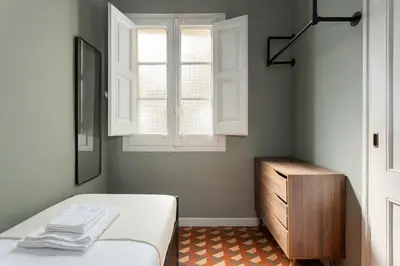 a bedroom with a bed and a window and a dresser at Spacious Stylish 4-bedroom Modernist Apartment in Barcelona