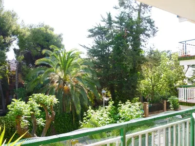 a green fence in a garden with trees and plants at Apartamento Annie a 100 metros de la playa en Vilanova i la Geltrú, completamente equipado. - ES-332-3 in Vilanova i la Geltrú