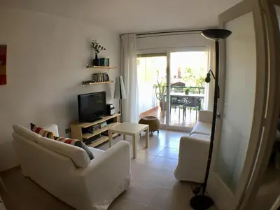 a living room with two white chairs and a television at Apartamento Annie a 100 metros de la playa en Vilanova i la Geltrú, completamente equipado. - ES-332-3 in Vilanova i la Geltrú