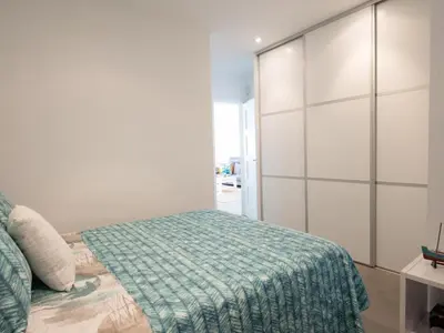 a bedroom with a bed with a green blanket at Apartamento cómodo frente al mar con acceso directo a la playa - ES-332-6 in Vilanova i la Geltrú